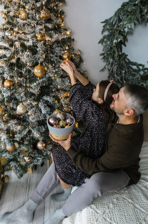 A heartwarming moment: A father and daughter decorate their Christmas tree together, creating lasting memories and holiday cheer. The scene is filled with love and festive spirit.の写真素材