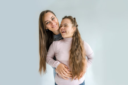 A heartwarming image of a mother and daughter with Down syndrome embracing each other. They are both smiling radiantly, showcasing their loving bond.の写真素材