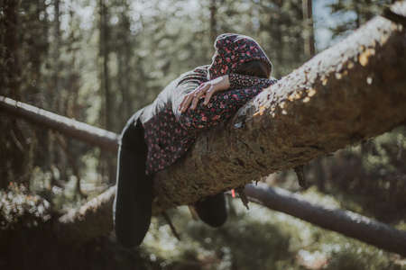 A young woman having a sun on a truck of a fallen treeの写真素材
