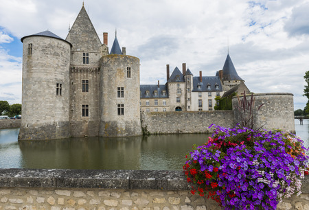 Castle in Sully sur Loire in France with purple flowers and a canal.のeditorial素材