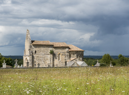 Church of Meillac Gours with sunlight and dark thunderstorm clouds.の写真素材