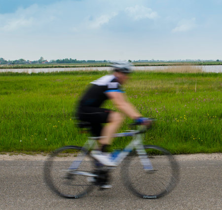 Fast biker on the road along a nature reserve of Staatsbosbeheer.の写真素材