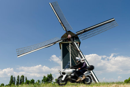 Mill at Batenburg on a dike with a motor with two persons in front.