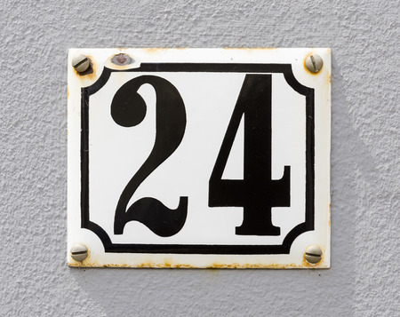 Sign of house number 24 in black karakters on a white sign and grey wall.の写真素材