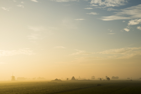 Peaceful sunrise with two wind mills, cows, fog in Streefkerk, Holland.の写真素材