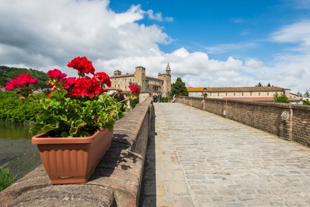 Monastero Bormida, Italy - May 29, 2016: Bridge, people, flowers, houses and Church of Monastero Bormida in Piedmont, Italyのeditorial素材