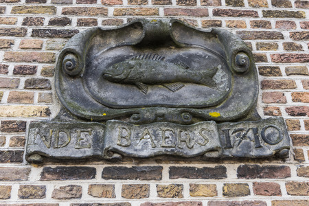 Statue in a wall of an old house with inscription: 'Inde Baers' in the city of Dordrecht, The Netherlands.のeditorial素材