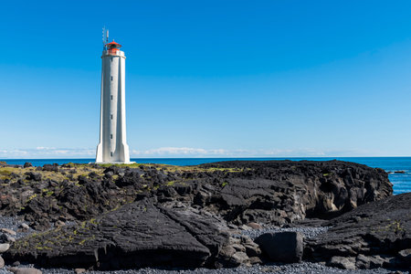 White lighthouse at Londrangar on Snaefellnes Westfjords on Iceland with volcanic lava rocks and oceanの写真素材