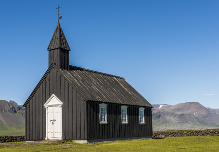 Black wooden Budakirkja at Saefellsnes with mountains in the background on Iceland.の写真素材