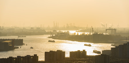 Nieuwe Maas in Evening Light with ships on the river, industrial areas and the harbor of Rotterdam in the Netherlands.のeditorial素材