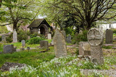 Gwithian, England - April 25, 2017: Graveyard in Gwithian with old gravestones, celtic cross and...