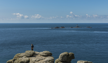 Lands' End, England - April 27, 2017: Lonely tourist at Lands' End with ocean and old lighthouse.のeditorial素材