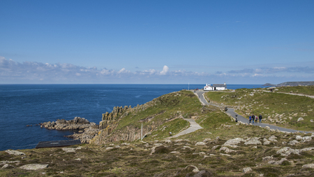 Lands' End, England - April 27, 2017: Tourists hiking to last/first house at Lands' End with ocean and blue sky.のeditorial素材