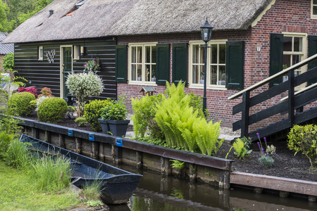 Giethoorn, The Netherlands - May 19., 2016:  Front of a monumental house in the small, picturesque town of Giethoorn with canal and rowing boat, Overijssel, Netherlands.のeditorial素材