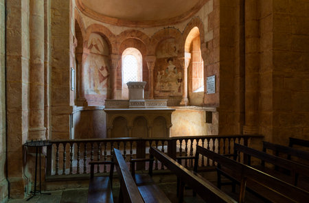 Gourdon, France - August 3, 2018: Interior with pink color, wooden benches and huge pilars of the Romanesque church in Gourdon, Saone-et-Loire, France.のeditorial素材