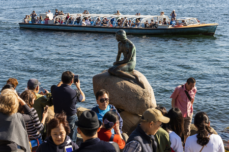 Copenhagen, Denmark - September 18, 2018: Mass tourism in Copenhagen at the Little Mermaid at the harbor of Copenhagen with tourist boat and many people.のeditorial素材