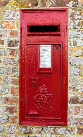Harbridge, England - October 22, 2018: Old red mail box in England in a brick wall with lots of...