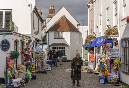 Lymington, England - October 25, 2018: Old lady walking in the street with touristic shops and white houses in typical English street.のeditorial素材