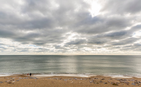 Barton on Sea, England - October 27, 2018: Sea with clouds and glistening water and running child...