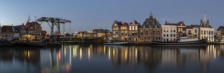 Maassluis, The Netherlands - February 26, 2019: Panorama of the harbor of Maassluis with old boats, tugs and monumental houses at night.のeditorial素材