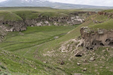Ani, Turkey - May 9, 2019: Caves and ruins of the old Armenian town Ani with churches and snowy mountains in the background, Turkey.のeditorial素材