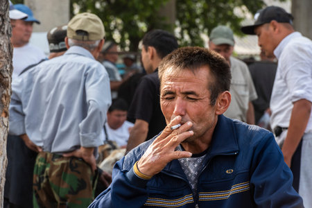 Osh, Kyrgyzstan - June 30, 2019: Smoking man on the livestock market in Osh, Kyrgyzstan.