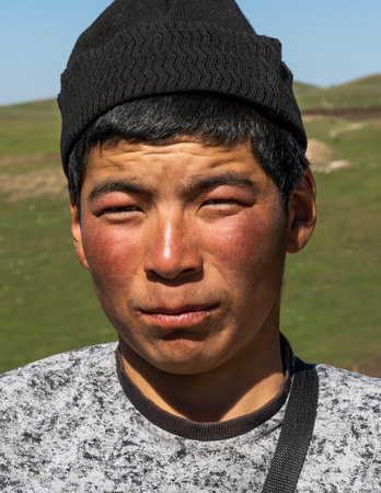 Toguz Toro, Kyrgyzstan - July 5, 2019: Portrait of a young man at the Toguz Toro Pass at the silk...