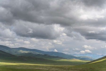 Steppe of Mongolia with dark clouds and a unpaved road.の写真素材