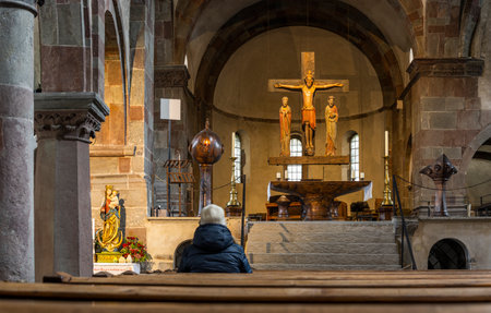 Innichen, Italy - October 4, 2020: Intirior of the Stiftskirche, church, of Innichen with old wooden roman crucifix and visitor sitting and praying in the church, Italy.のeditorial素材