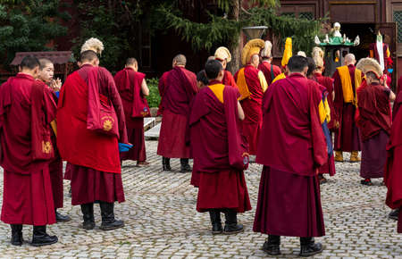Ulaanbaatar, Mongolia - August 25, 2019: Gandantegchinlen Monastery in Ulaanbaatar with several monks dressed in a red habit waiting to enter the temple.のeditorial素材
