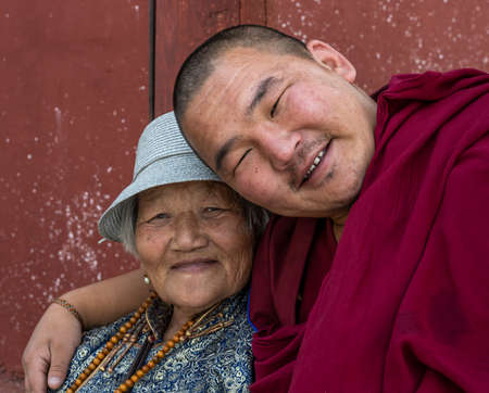 MÃ¶rÃ¶n, Mongolia - August 17, 2019: Buddhist monk wit red habit clothes in Buddhist temple with woman laughing in MÃ¶rÃ¶n, Mongolia.のeditorial素材