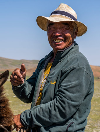 Tsagaanhairhan, Mongolia - August 9, 2019: Mongolian shepherd on horseback with hat and on the...
