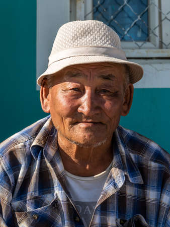 Lun, Mongolia - August 27, 2019: Portrait of an old Mongolian man with blue shirt and white hat.のeditorial素材