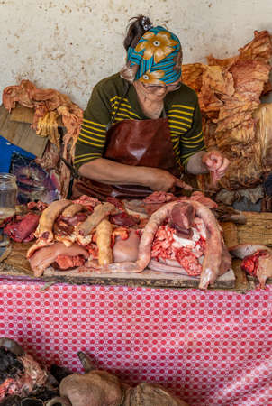 Moron, Mongolia - August 13, 2019: Woman butcher with several heads of cows with horns lie on the ground with preperation of the meat for customers in MÃ¶rÃ¶n, Mongolia,のeditorial素材