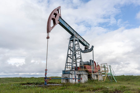 Pumpjack on a meadow on a summers day with clouds.