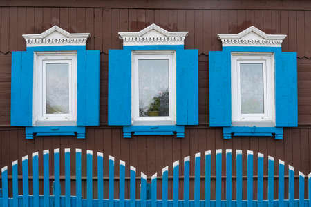 Russian old brown log cabin with blue and white shutters near Lake Baikal.の写真素材