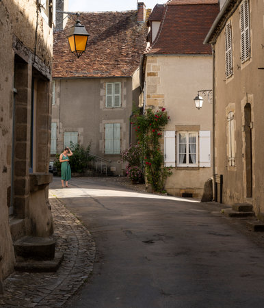 Saint-Benoit-du-Sault, France - June 14, 2022: Alley with woman on the street with old houses in Saint-Benoit-du-Sault, one of the 'Plus Beaux Village de France'.のeditorial素材