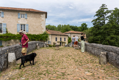 Saint-Jean-de-Cole, France - June 12, 2022: Old stone bridge with people in summer in the village of Saint-Jean-de-Cole one of the 'Plus beaux village de France'.のeditorial素材