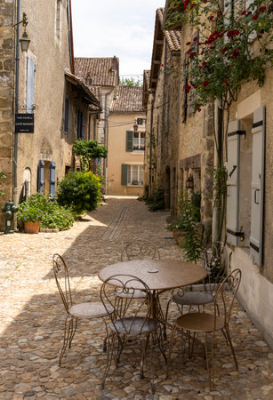 Saint-Jean-de-Cole, France - June 12, 2022: Small street with chairs and table and rose in the village of Saint-Jean-de-Cole one of the 'Plus beaux village de France'.のeditorial素材