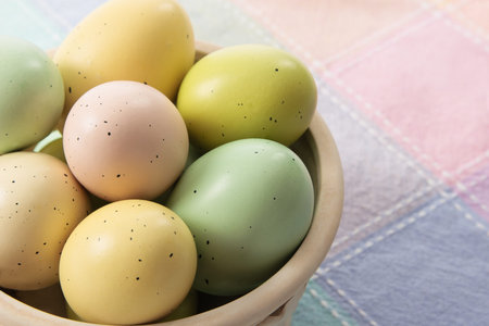 Speckled pastel colored Easter Eggs rest in a ceramic basket with copyspace on right