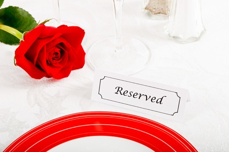 Close up of a romantic red and white place setting shows a reserved table at an elegant restaurant ready to celebrate an anniversary or Valentine's Day.の写真素材