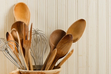 A collection of wooden spoons and wire whisks against a weathered wood backgroundの写真素材