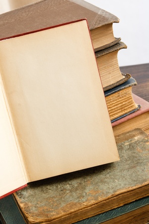 A blank page offers copy space against a background of stacked antique booksの写真素材