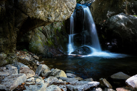 Small mountain waterfall on the rocks covered with moss in the forestの写真素材
