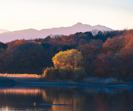 Autumn landscape with lake and mountains in the background at sunset.の写真素材