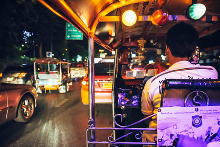 BANGKOK - JUNE 10, 2015: An unidentified tuktuk driver stuck in a night traffic jam, on June 10, 2015, in Bangkok, Thailand. Traffic jams are a constant in a city like Bangkokのeditorial素材