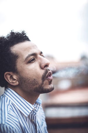 Confident attractive mulatto man smoking a cigarretteの写真素材