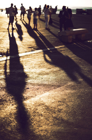 Shadows of people walking in a street of the city at the sunsetの写真素材