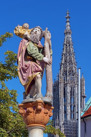 Statue of St Christopher carrying the Christ Child and Tower of the Ulm Minster, Ulm, Germanyの写真素材