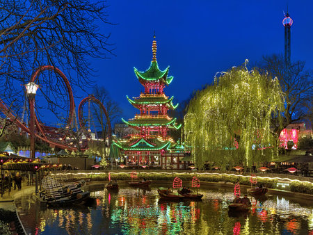 COPENHAGEN, DENMARK - DECEMBER 14, 2015: Evening view of Tivoli Gardens with Chinese pagoda, Dragon Boat lake and Daemonen roller coaster. Tivoli is the most-visited theme park in Scandinavia.のeditorial素材